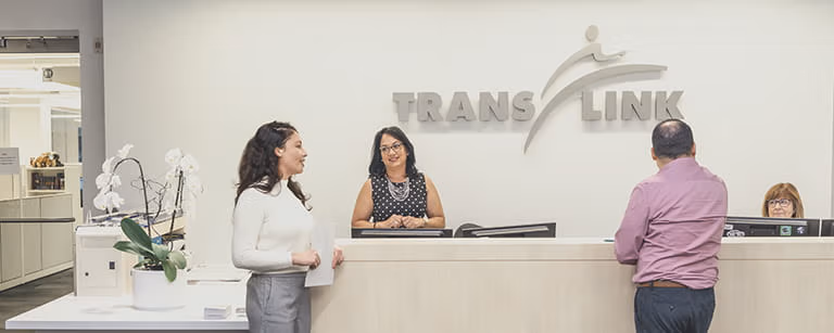 Two people standing in front of a reception desk inside TransLink's head office