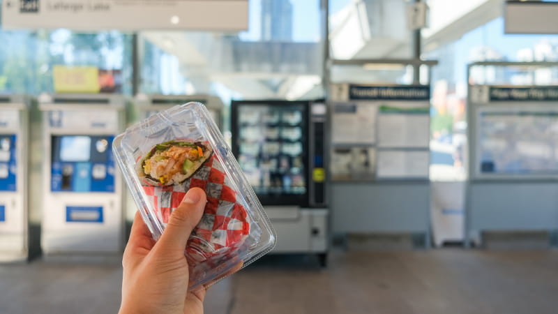 A sushi wrap in front of a vending machine at Lafarge Lake–Douglas Station
