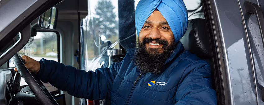 A CMBC Shuttle operator sitting in the driver seat smiling for the camera