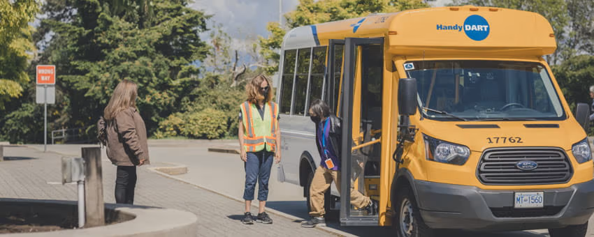 HandyDART driver assisting an elderly passenger with exiting the bus.