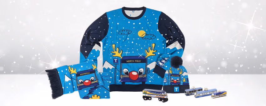 TransLink holiday sweater, scarf, and hat with festive Reindeer bus designs on them, plus miniature train models.
