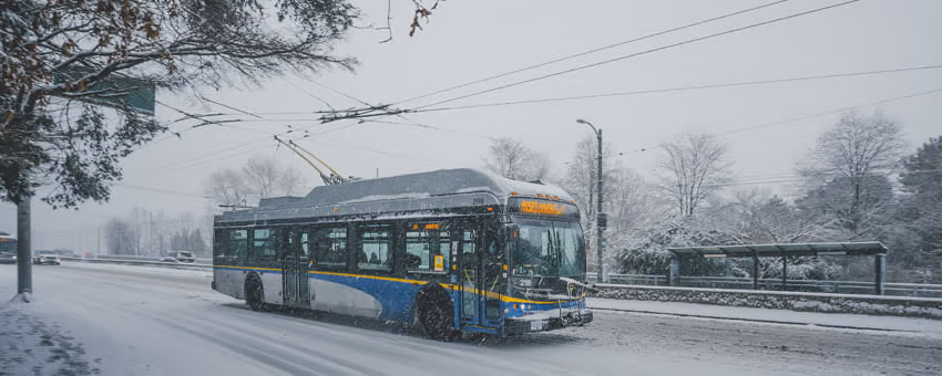 Bus driving on icy road on a snowy day.