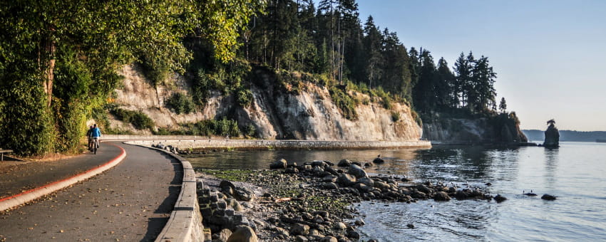 The Stanley Park Seawall at sunset with a couple walking in the background